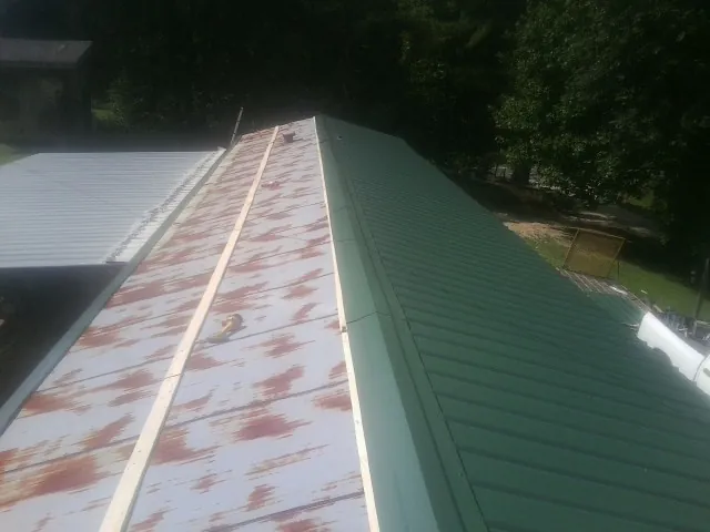Old rusted panels beside newly installed green metal roofing — Wind Damage Roof Repair by Roofing Brothers in Yankeetown