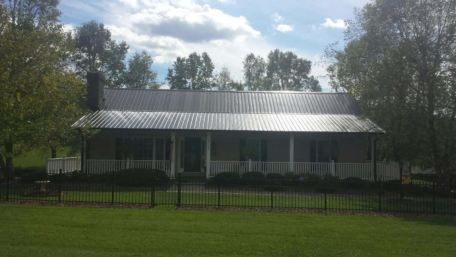 Gray metal roof on a brick ranch with a full width front porch — Gutter Guard Installation work by our crew in Yankeetown