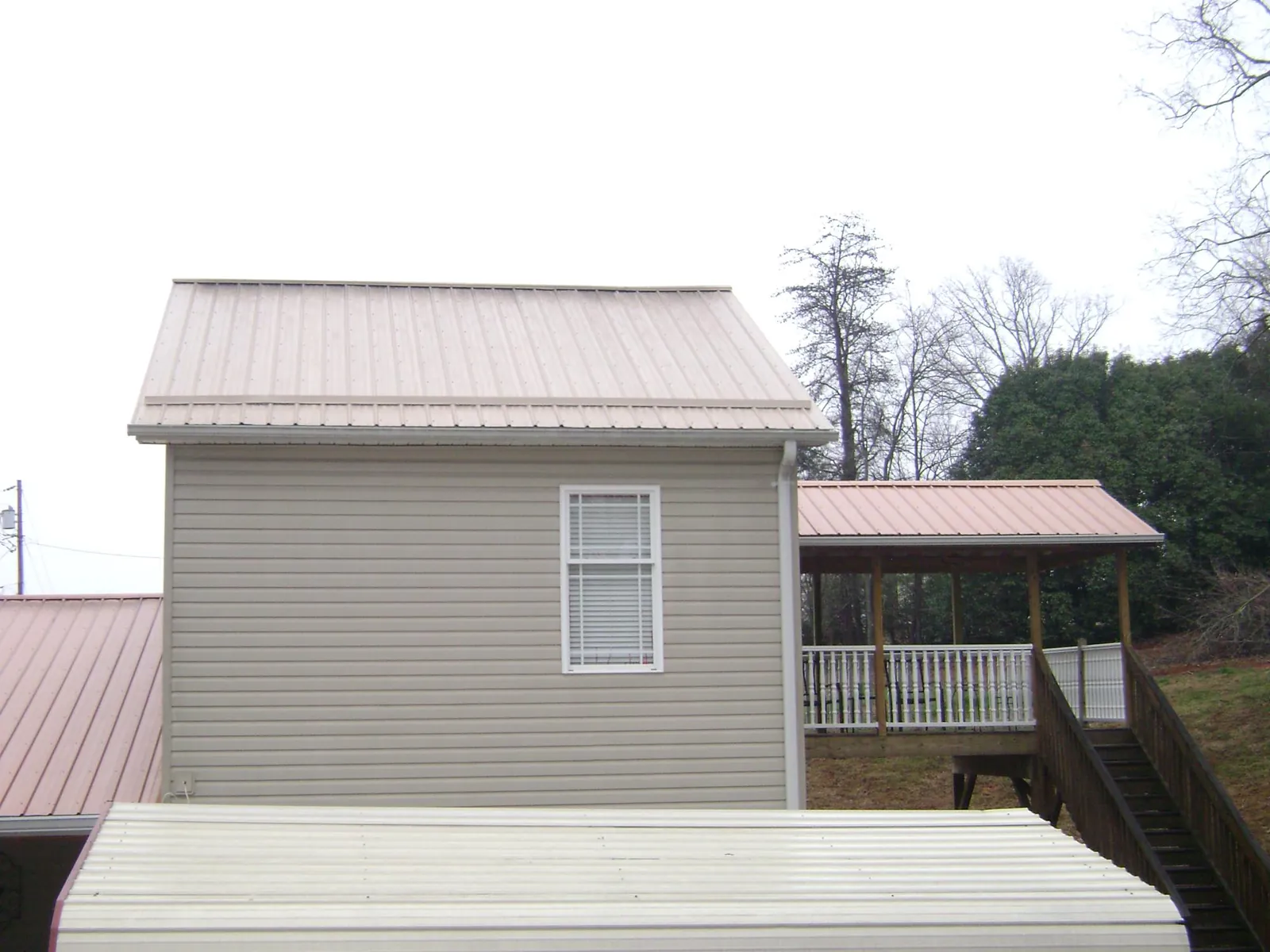 Tan metal roofs on a two story addition and attached porch, from a Roof Replacement job in Yankeetown