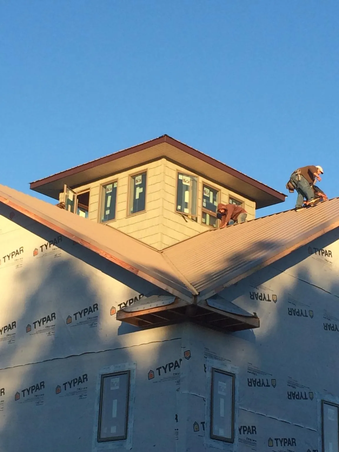 Roofers working around a rooftop cupola on a new metal roof at sunset — Roof Waterproofing in Yankeetown by Roofing Brothers